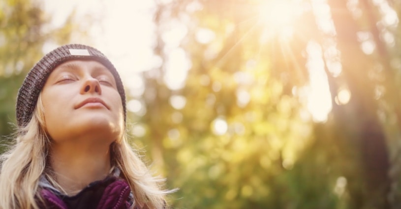 Frau in der Natur, atmet durch während die Sonne strahlt